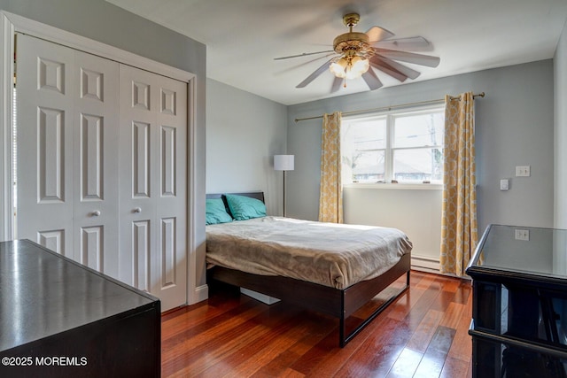 bedroom featuring a closet, wood-type flooring, ceiling fan, and a baseboard radiator