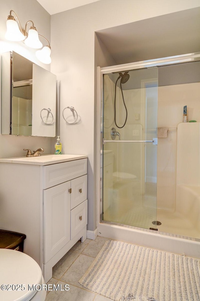 bathroom with vanity, toilet, a stall shower, and tile patterned flooring