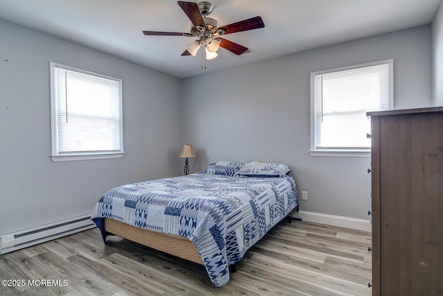 bedroom with light wood-style floors, multiple windows, baseboard heating, and baseboards