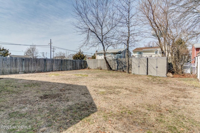 view of yard featuring a storage shed, an outbuilding, and a fenced backyard