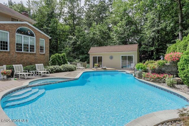 view of pool featuring a patio, an outdoor structure, and a pool with connected hot tub