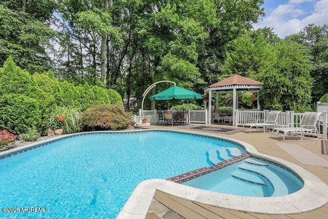 view of pool featuring a gazebo, a pool with connected hot tub, a patio, and fence