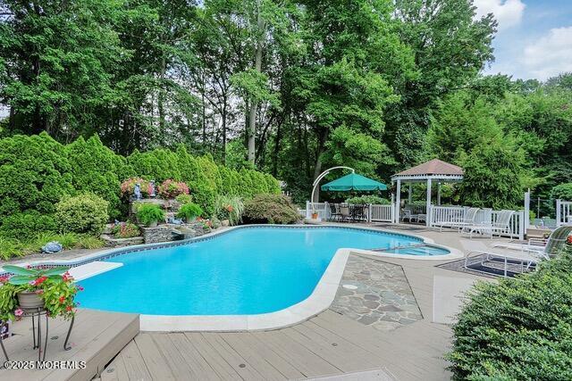 outdoor pool with a gazebo, a deck, a patio, and fence