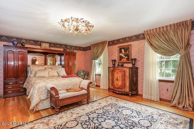 bedroom with multiple windows, wallpapered walls, and wood finished floors