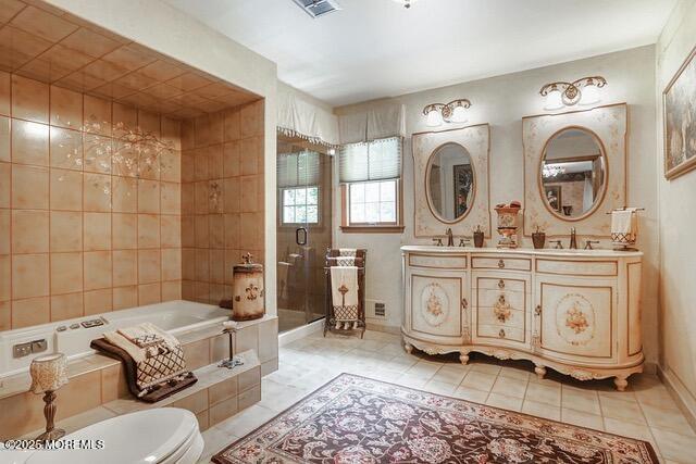 full bathroom featuring tile patterned floors, a garden tub, double vanity, and a sink