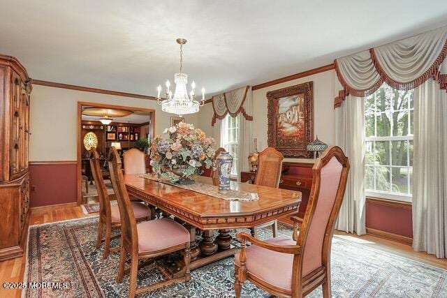 dining room with an inviting chandelier, crown molding, and light wood finished floors