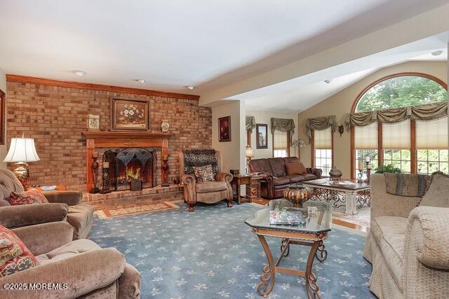 carpeted living area with a brick fireplace, brick wall, and lofted ceiling