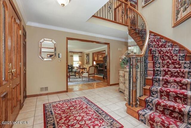 foyer entrance featuring light tile patterned flooring, visible vents, stairs, and crown molding