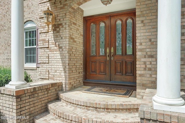 property entrance featuring covered porch and brick siding