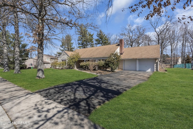 view of front of home with driveway, a front yard, a chimney, and an attached garage