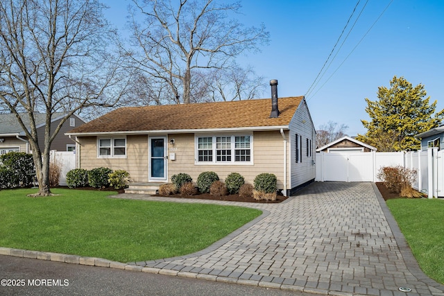 view of front of house featuring fence, decorative driveway, a front lawn, and a gate