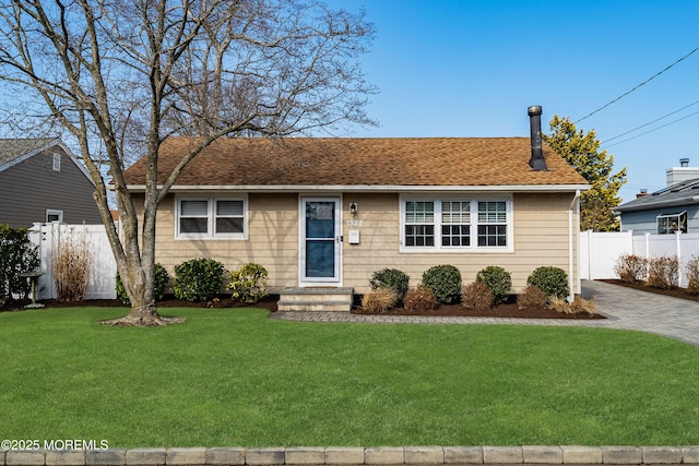 view of front of property with a front yard, decorative driveway, fence, and a shingled roof