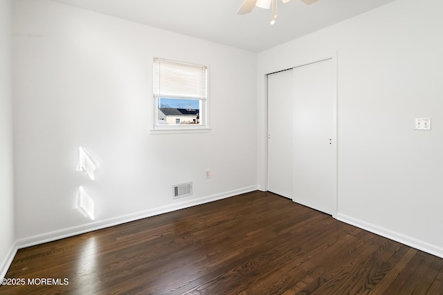 unfurnished bedroom featuring visible vents, baseboards, dark wood finished floors, a closet, and a ceiling fan