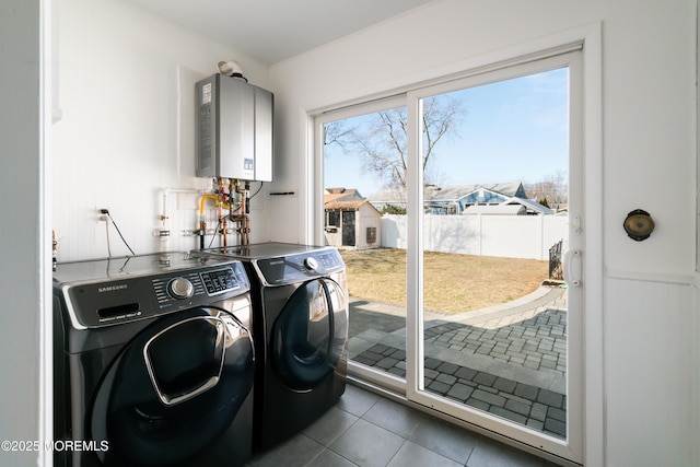 laundry area with water heater, washer and clothes dryer, and dark tile patterned flooring