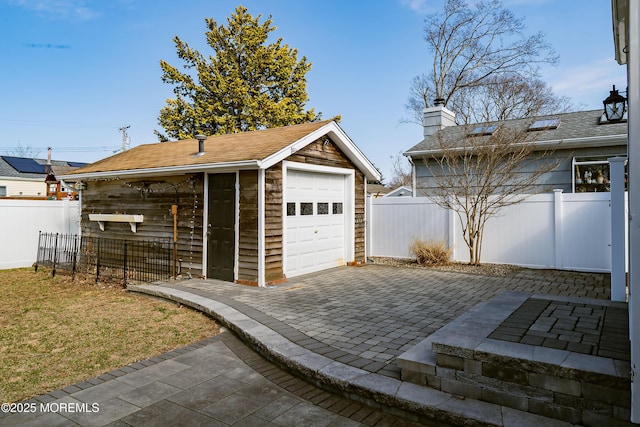 detached garage with decorative driveway and fence