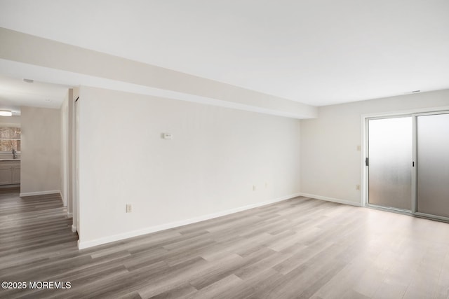 spare room with a sink, baseboards, and wood finished floors