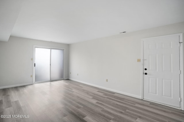 empty room featuring visible vents, baseboards, and wood finished floors