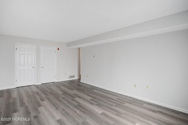 empty room featuring visible vents, baseboards, and wood finished floors