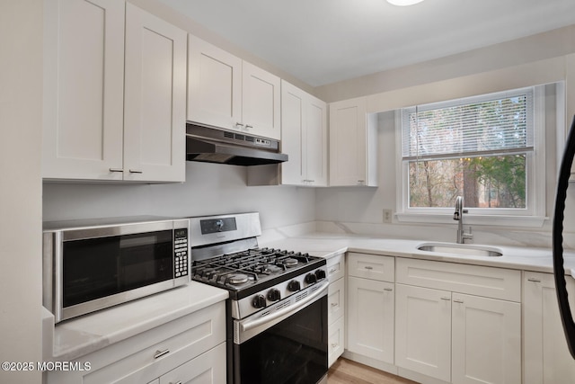 kitchen featuring a sink, stainless steel appliances, light countertops, white cabinets, and under cabinet range hood