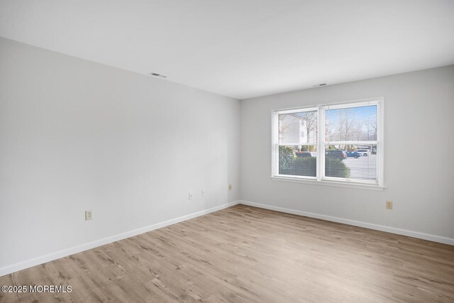 unfurnished room featuring wood finished floors, visible vents, and baseboards