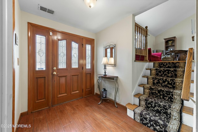 entryway featuring visible vents, stairs, lofted ceiling, and wood finished floors