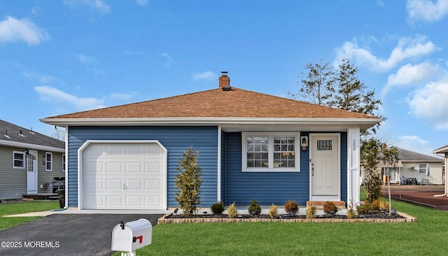 view of front facade with a front lawn, an attached garage, driveway, and a chimney