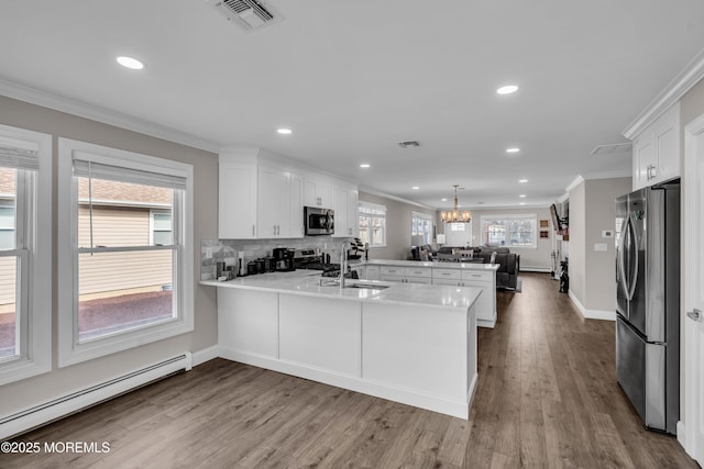 kitchen with visible vents, a peninsula, stainless steel appliances, open floor plan, and baseboard heating