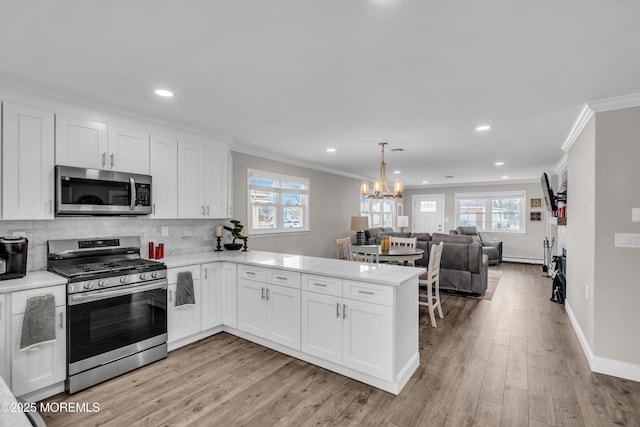 kitchen featuring tasteful backsplash, appliances with stainless steel finishes, a peninsula, and light countertops