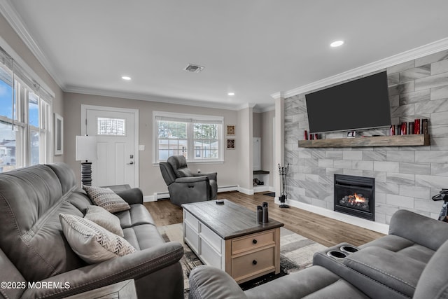 living room with visible vents, a fireplace, wood finished floors, and ornamental molding