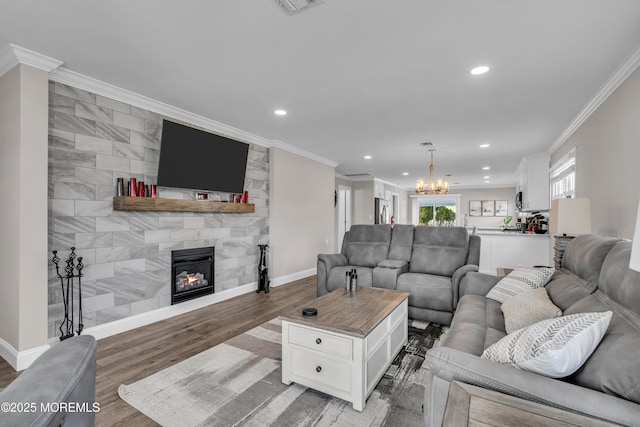 living area featuring baseboards, an inviting chandelier, a tile fireplace, crown molding, and light wood-type flooring