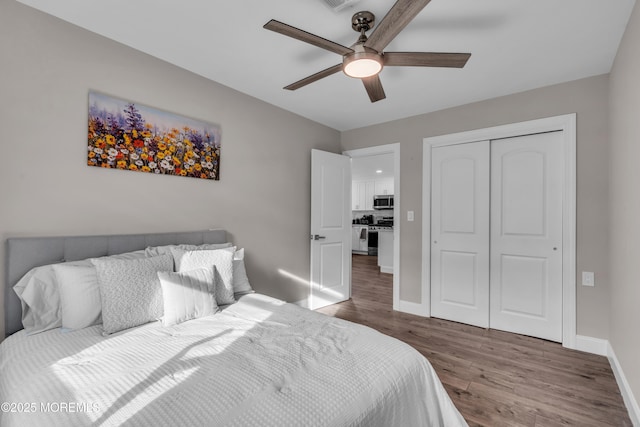 bedroom with ceiling fan, wood finished floors, a closet, and baseboards