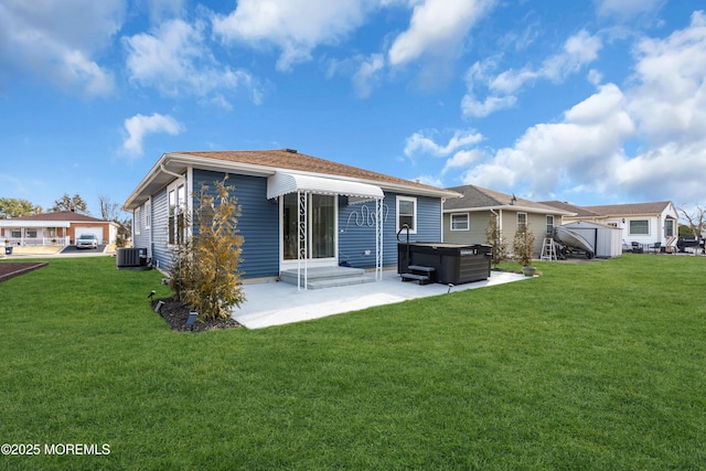 rear view of property with a yard, a patio, central AC, and a hot tub