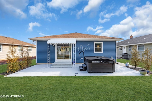 rear view of property featuring a yard, a patio area, and a hot tub