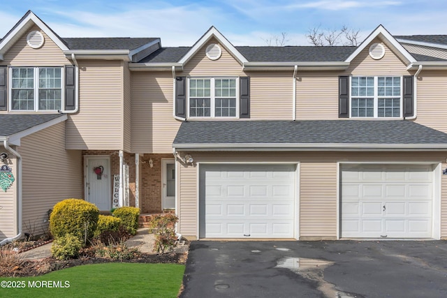 view of front facade featuring a garage, roof with shingles, and driveway