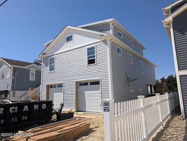 view of front facade with board and batten siding, an attached garage, and fence