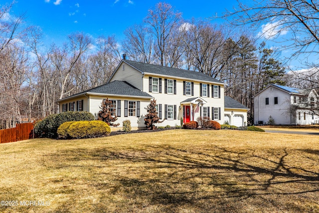 view of front of property with a front lawn, roof with shingles, an attached garage, and fence