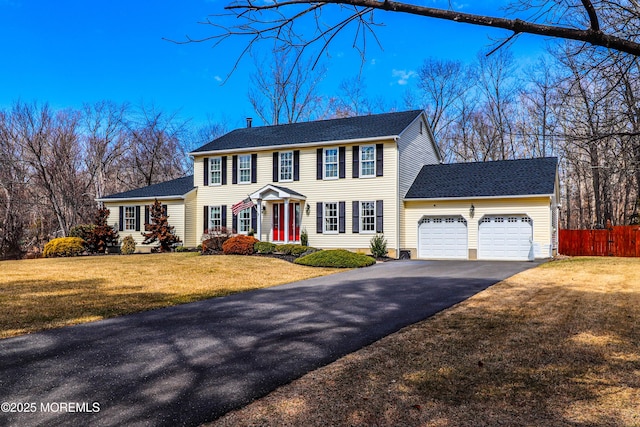 view of front of home featuring a garage, a front lawn, driveway, and fence