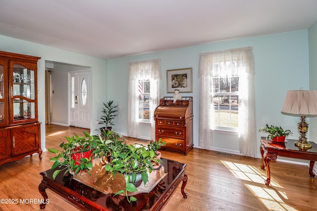 living room with visible vents, baseboards, and wood finished floors