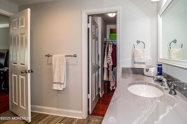 bathroom featuring vanity, baseboards, and wood finished floors