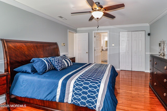 bedroom featuring visible vents, wood finished floors, a closet, and ornamental molding