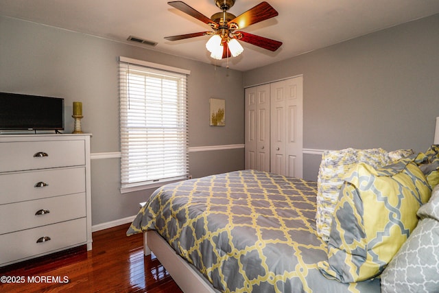 bedroom featuring baseboards, visible vents, dark wood finished floors, ceiling fan, and a closet