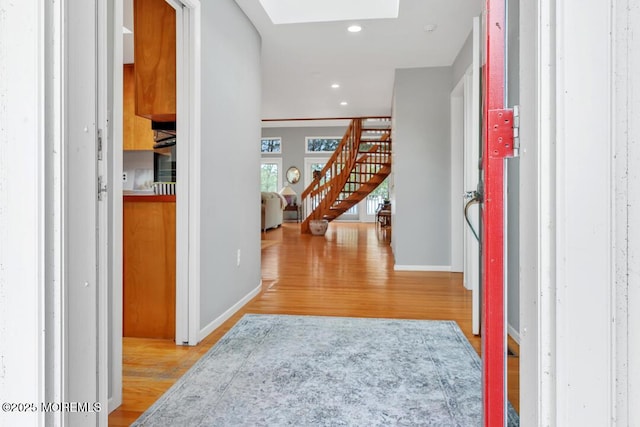 foyer entrance with stairway, a skylight, recessed lighting, and wood finished floors