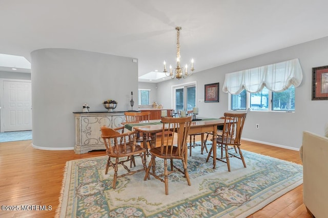 dining room with a chandelier, baseboards, and light wood-style flooring