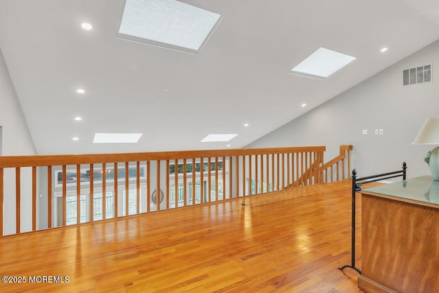 corridor with lofted ceiling with skylight, visible vents, recessed lighting, and wood finished floors