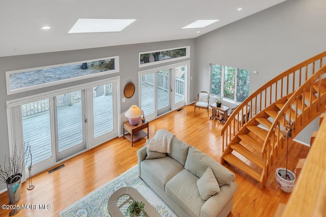 living area featuring visible vents, a skylight, stairs, and wood finished floors