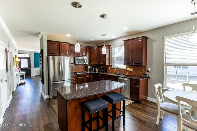 kitchen with tasteful backsplash, a center island, dark wood finished floors, stainless steel appliances, and a sink