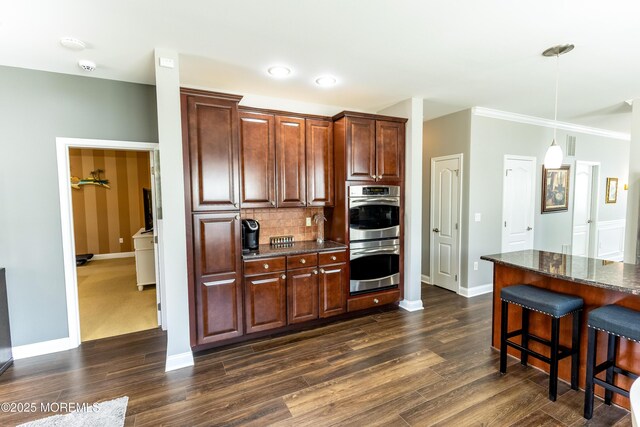 kitchen with double oven, a kitchen breakfast bar, dark wood-style floors, and backsplash