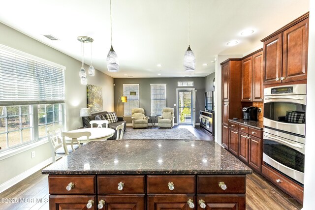 kitchen with hanging light fixtures, dark wood-style flooring, a wealth of natural light, and stainless steel double oven