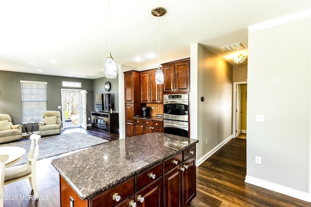 kitchen with visible vents, stainless steel double oven, baseboards, dark wood-style flooring, and hanging light fixtures