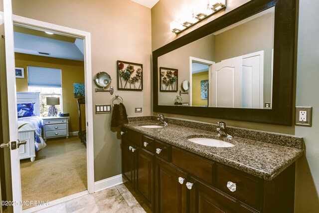 ensuite bathroom with a sink, connected bathroom, baseboards, and double vanity